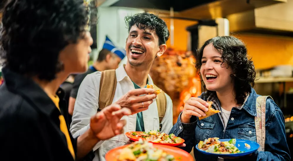 Three young people enjoy tacos in the streets of Mexico City