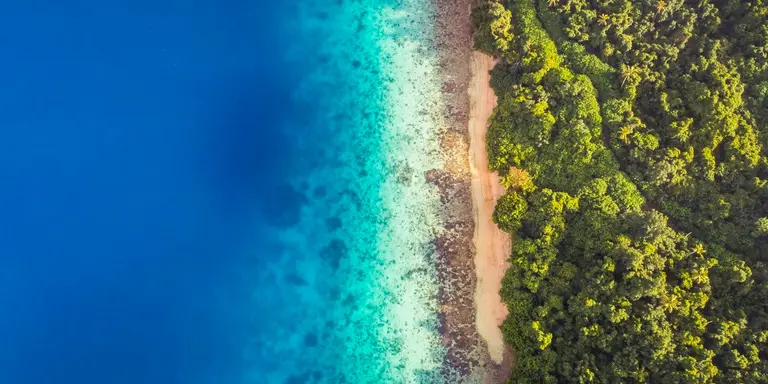 Aerial view of calm aqua marine blue water with tropical secluded beach