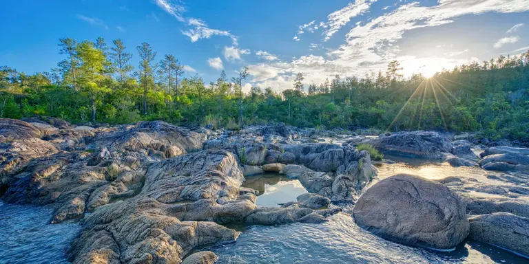 Beautiful river on pools of cascading water with pine trees in the background