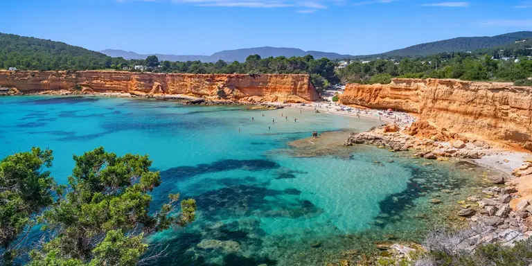 Bright light of a summer noon, transparent waters marbled with Posidonia meadows, sparse bathers on the beach.