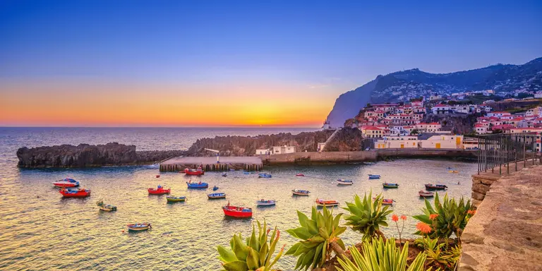The beautiful fishing village, boats in the water and steep cliff in the background