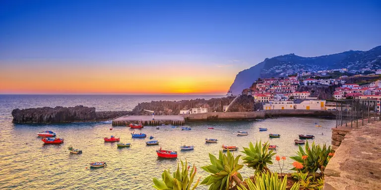 The beautiful fishing village, boats in the water and steep cliff in the background
