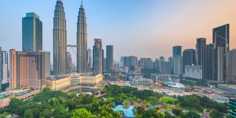 Sunset skyline view of Kuala Lumpur featuring the Petronas Twin Towers, an interlinked pair of 88-storey skyscrapers
