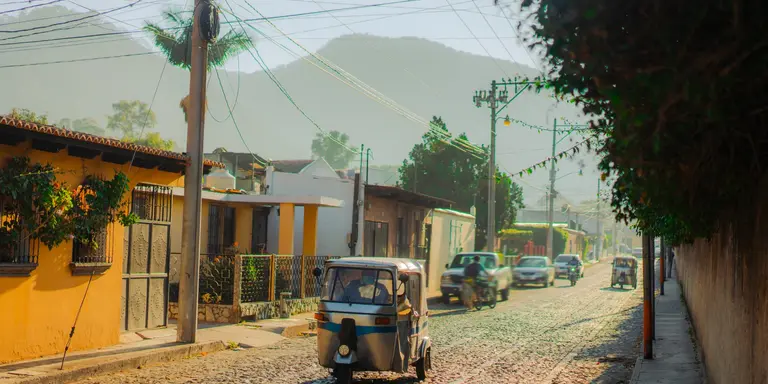 Tuk-tuk three wheeled vehicle driving along historical street in Guatemala