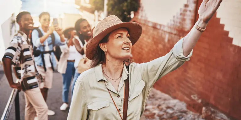 Woman, city guide and group of happy tourists, pointing at local architecture