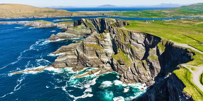 Amazing wave lashed cliffs surrounded be green hills on a sunny day