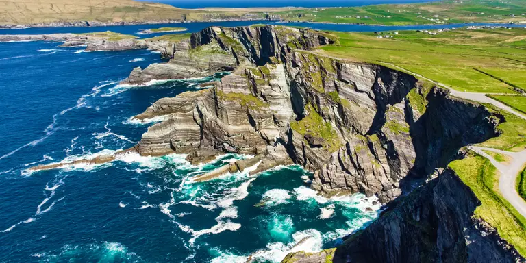 Amazing wave lashed cliffs surrounded be green hills on a sunny day