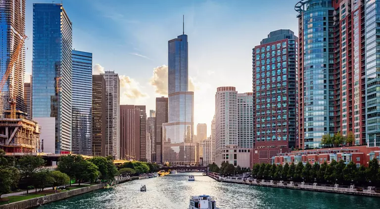 Cityscape from Chicago River Waterfront at Dusk. Small boats and tourist ferries cruising towards the Michigan Lake