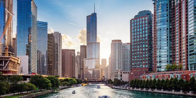 Cityscape from Chicago River Waterfront at Dusk. Small boats and tourist ferries cruising towards the Michigan Lake