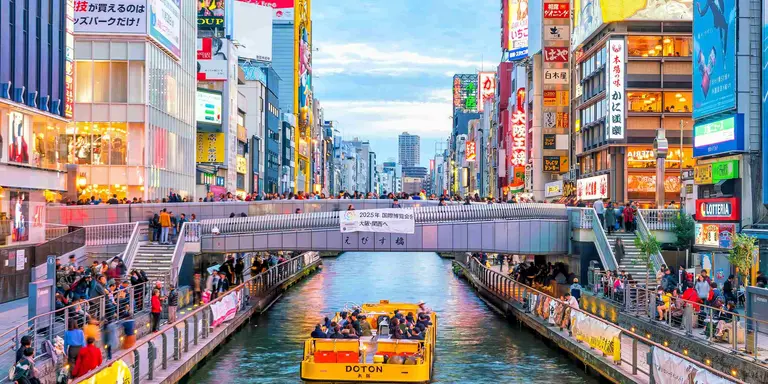 Boat floating down canal on Dotonbori shopping street, a famous destination for traveling and shopping in Osaka