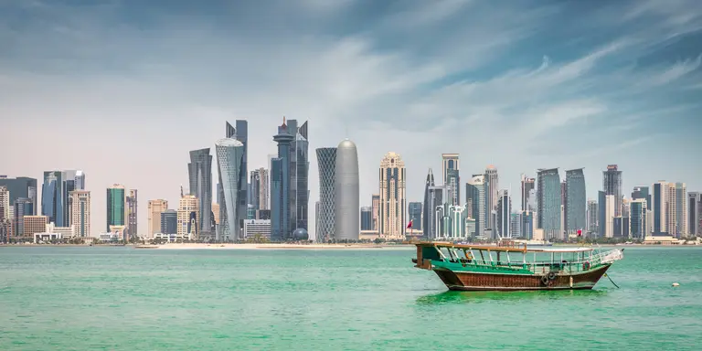 Waterfront panorama at Doha Corniche Promenade with anchored typical qatari Dhow Cruise Boat 