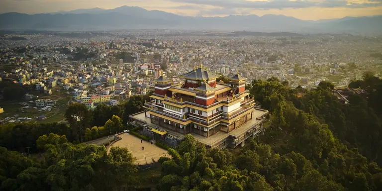 "Pullahari Monastery, Buddhist pilgrimage site on northern hill in Kathmandu Valley with city and mountains in background. "