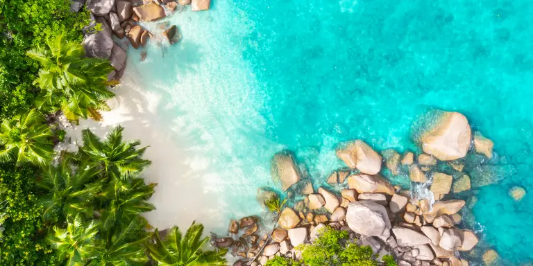 Aerial view from above of beach and bright blue waters of coastline