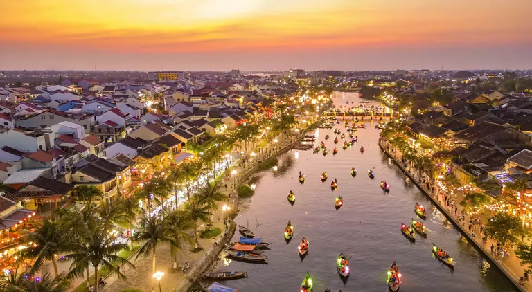 Hoi An at dusk with boats cruising on Thu Bon River with lanterns
