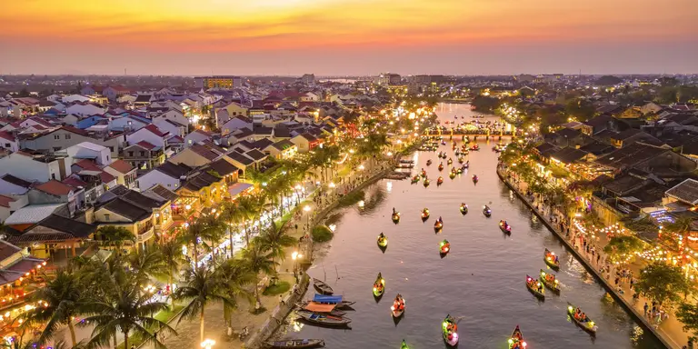 Hoi An at dusk with boats cruising on Thu Bon River with lanterns