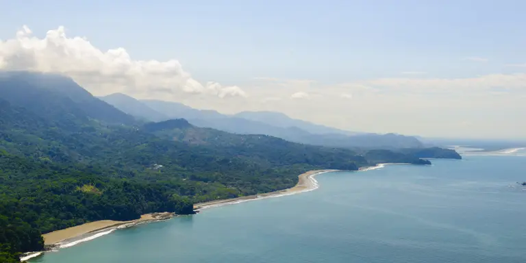 Vibrant tropical forests flow down from the mountains to the sandy beaches along the coast. Aerial view of the Costa Ballena near Dominical, Costa Rica