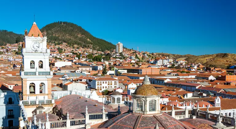 View of white colonial cathedral clocktower and red roofs in Sucre, Bolivia known as the White City