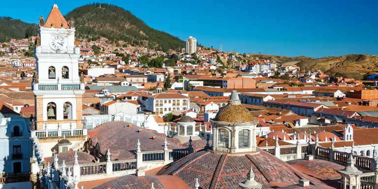 View of white colonial cathedral clocktower and red roofs in Sucre, Bolivia known as the White City