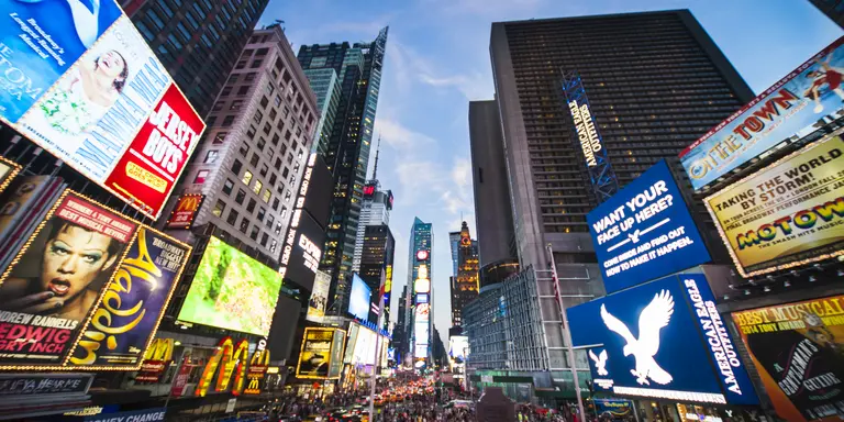 Tourists crossing Times Square surrounded by bright lights and advertisements