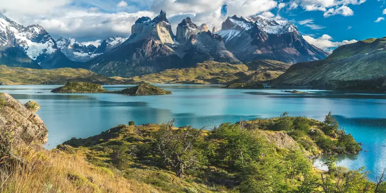 Blue lake on a snowy mountains background and cloudy sky
