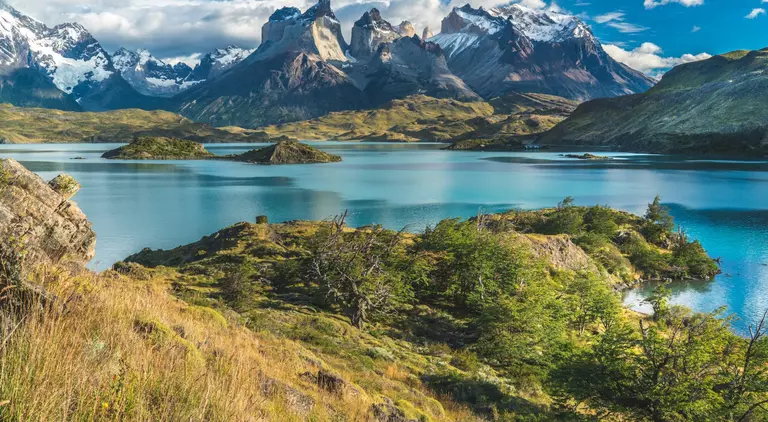 Blue lake on a snowy mountains background and cloudy sky