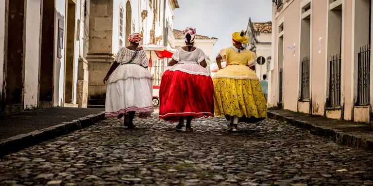 Group of "Baianas" walking in the famous Pelourinho cobblestone road in Salvador, Bahia, Brazil