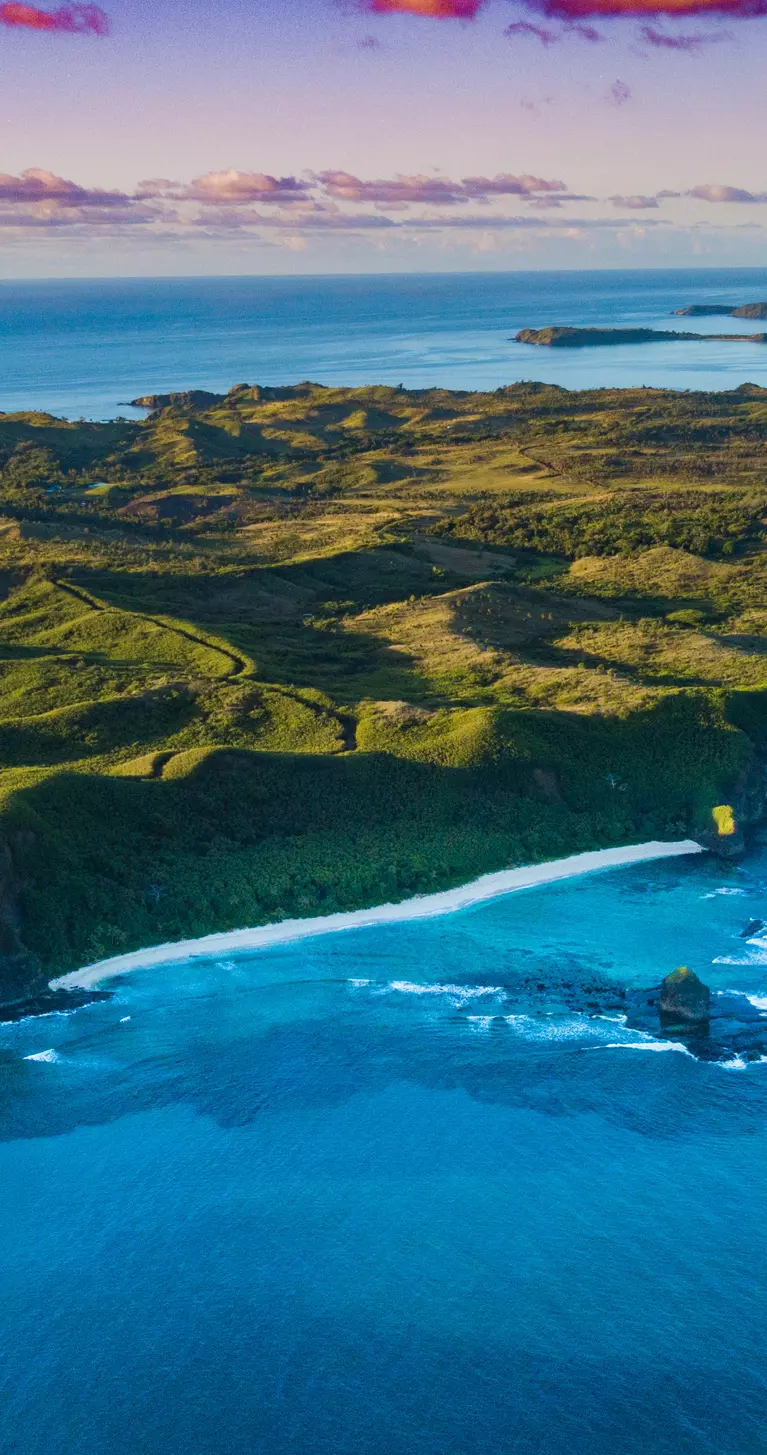 Aerial view of a Fiji island with bright green foliage and sunset sky