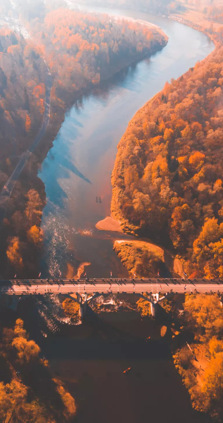 Aerial morning view of the golden autumn in Sigulda, Latvia. Gauja river bridge, cable car and golden forest.