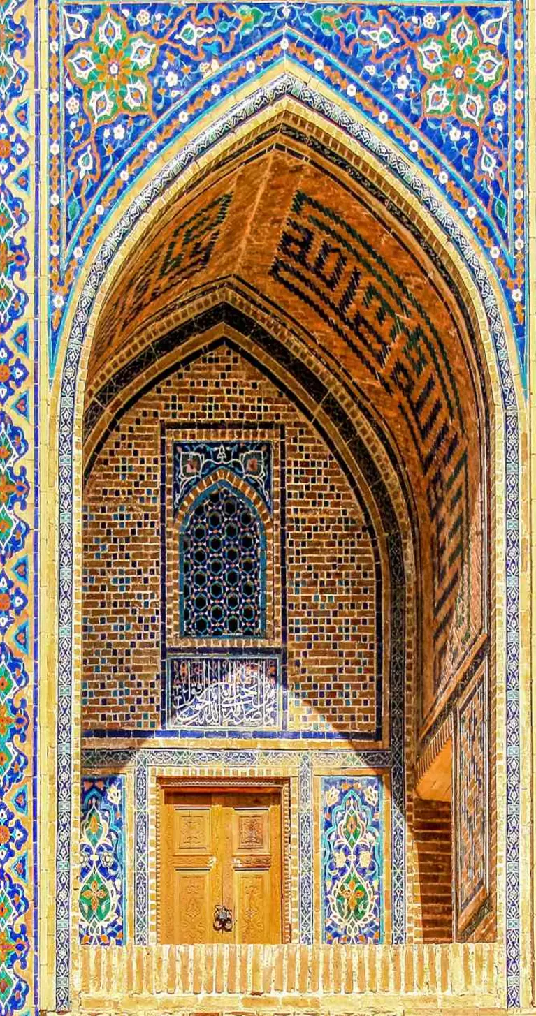 Sherdor Madrassah facade with blue, yellow and green tiles, wall with tall arches and windows