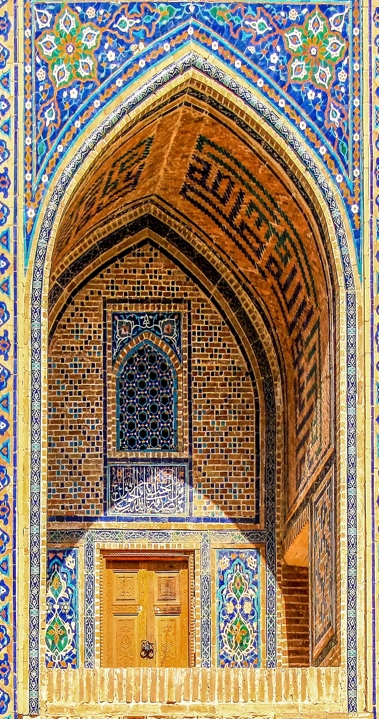 Sherdor Madrassah facade with blue, yellow and green tiles, wall with tall arches and windows