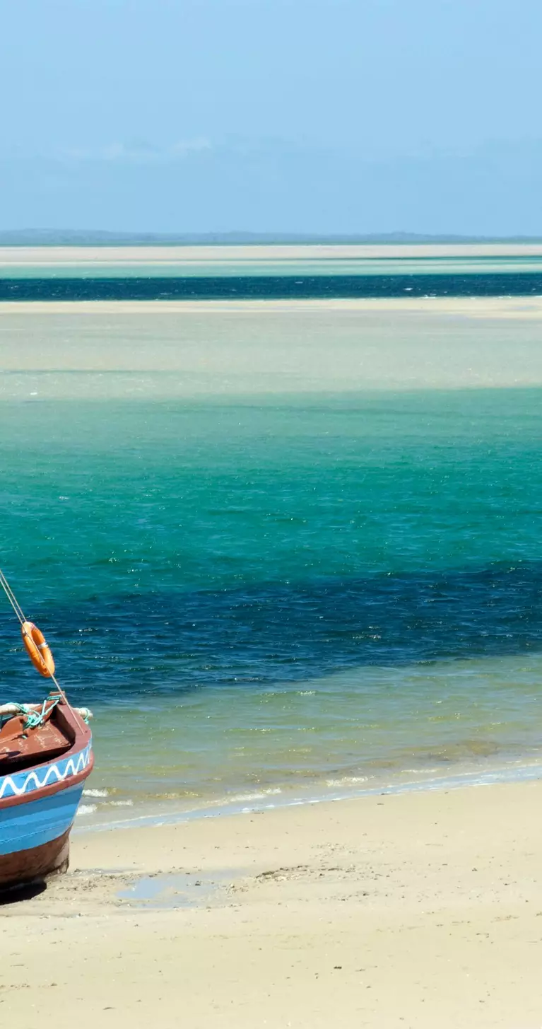 A Dhow (boat) sitting at the water's edge on a beach
