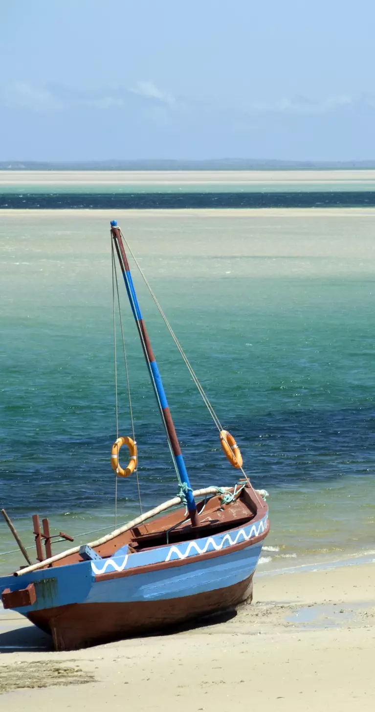 A Dhow (boat) sitting at the water's edge on a beach