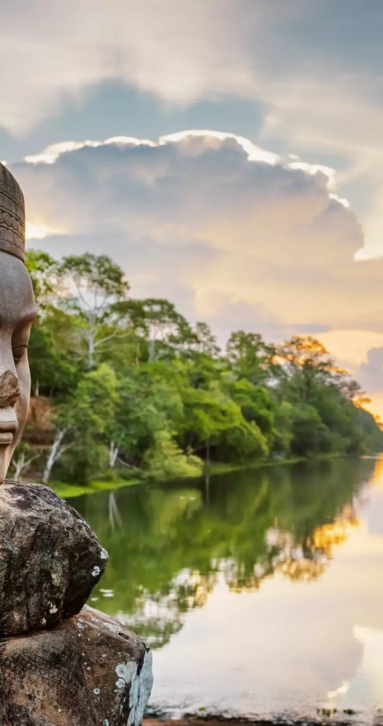 Stone face Asura over moat on causeway near South Gate of Angkor Thom in Siem Reap, Cambodia