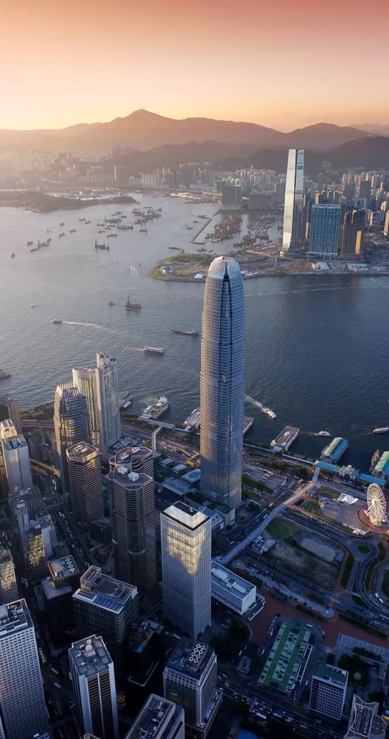 Dramatic skyline of Hong Kong Island and busy ships navigates across the Victoria Harbour during beautiful sunset