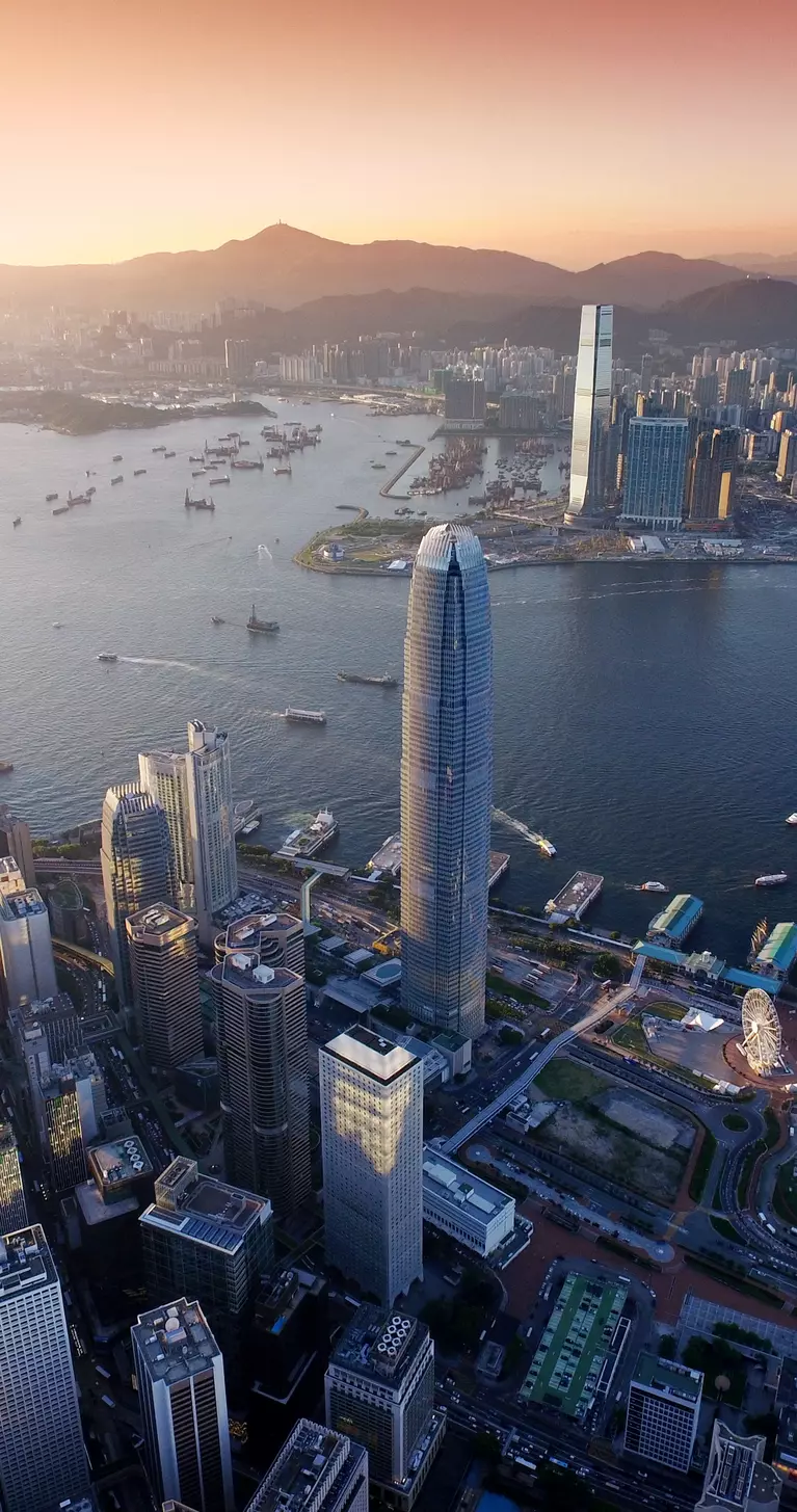 "Dramatic skyline of Hong Kong Island and busy ships navigates across the Victoria Harbour during beautiful sunset "
