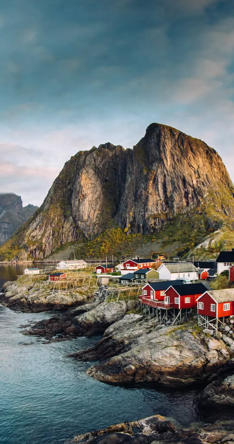 Dramatic sunset clouds moving over steep mountain peaks of Norwegian fishing village in the Lofoten Islands in Norway. 