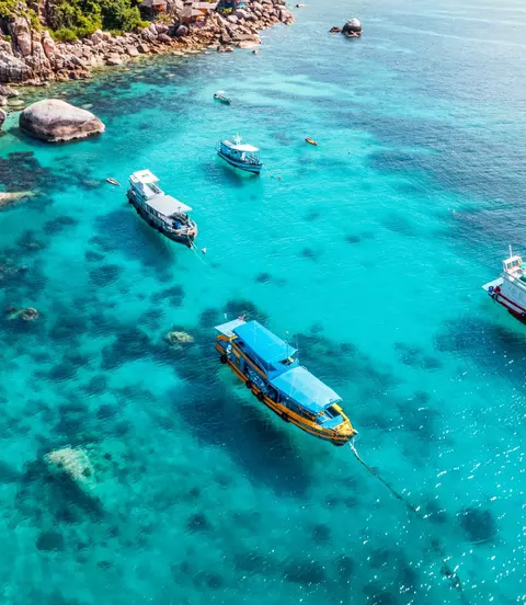 Boats and crystal clear waters at the bay dive site from above