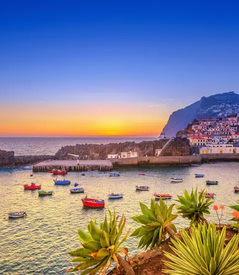 The beautiful fishing village, boats in the water and steep cliff in the background