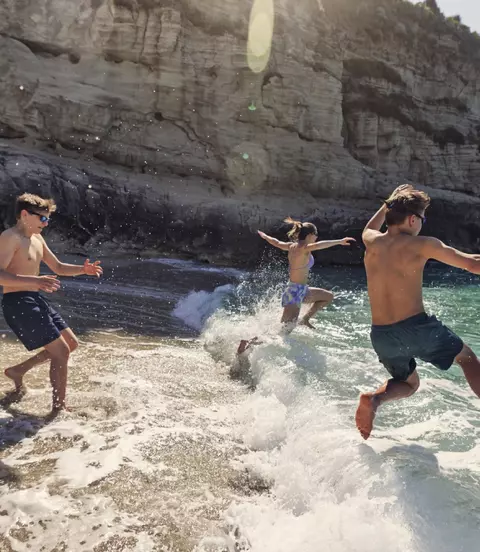 A bunch of happy teenagers running into the surf in Italy