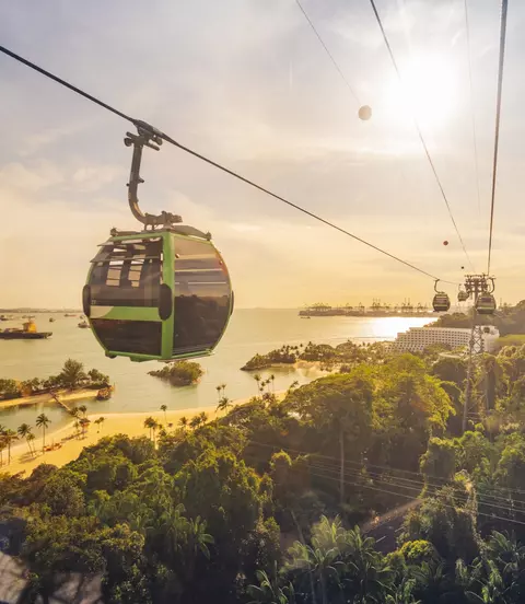 Cable car trip to Sentosa Island, Singapore. Aerial view showing lush green forest and sandy beach below