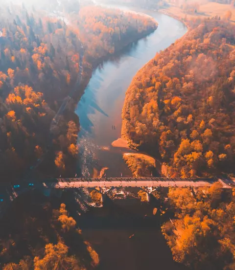 Aerial morning view of the golden autumn in Sigulda, Latvia. Gauja river bridge, cable car and golden forest.