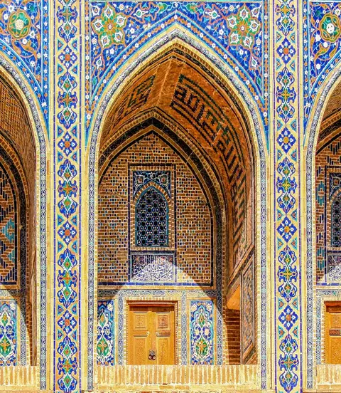 Sherdor Madrassah facade with blue, yellow and green tiles, wall with tall arches and windows