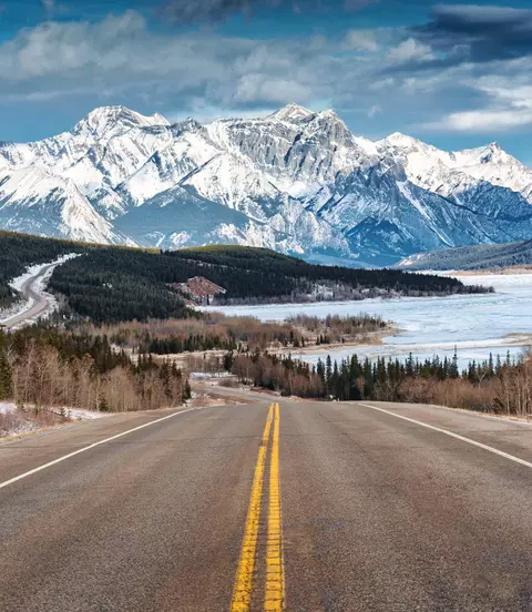 Beautiful scenery of Road trip on highway with rocky mountains and frozen lake