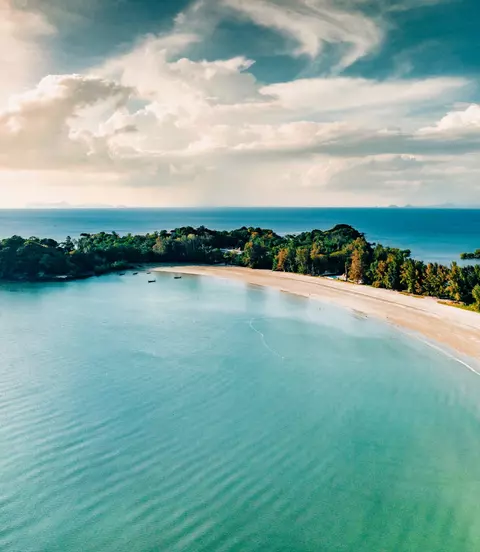Aerial point of view towards the island bay and coast under sunny blue summer sky.