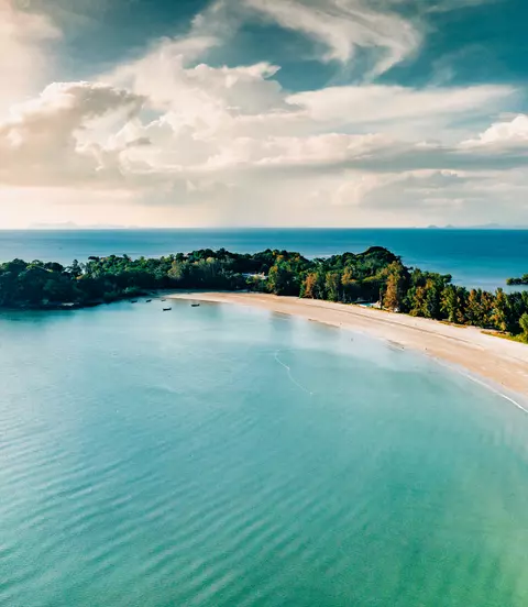 Aerial point of view towards the island bay and coast under sunny blue summer sky.