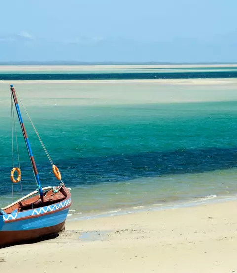 A Dhow (boat) sitting at the water's edge on a beach