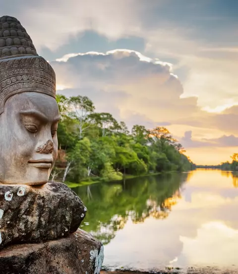 Stone face Asura over moat on causeway near South Gate of Angkor Thom in Siem Reap, Cambodia