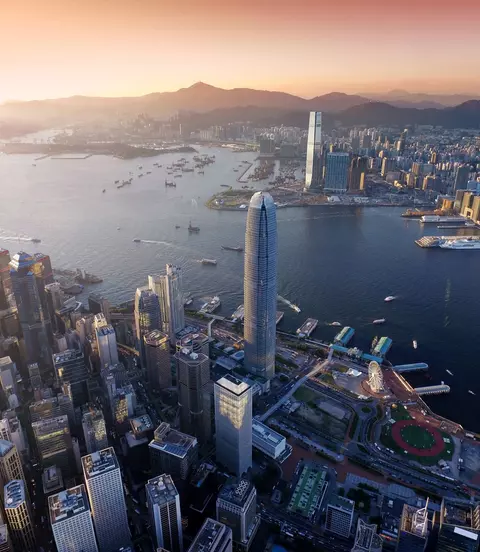 Dramatic skyline of Hong Kong Island and busy ships navigates across the Victoria Harbour during beautiful sunset