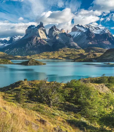 Blue lake on a snowy mountains background and cloudy sky