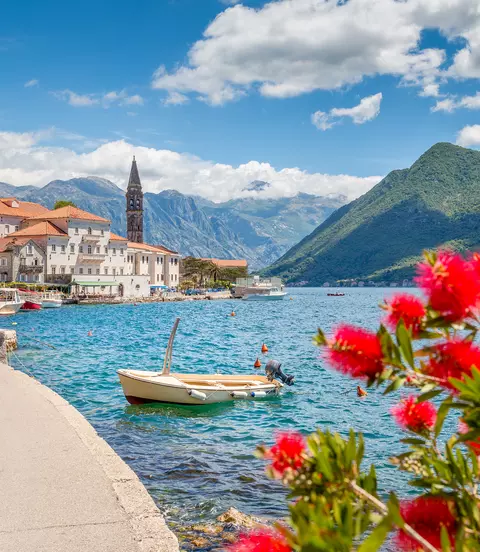 Panorama view of Perast at famous Bay of Kotor with blooming flowers on a beautiful sunny day with blue sky and clouds in summer